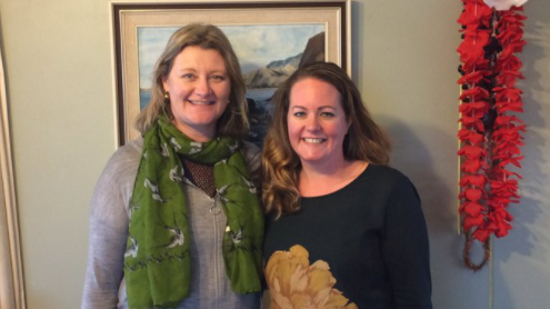 Two women stand close together smiling