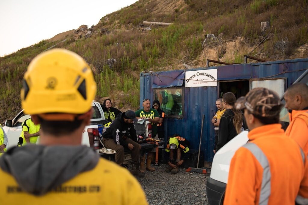 A group of forestry workers stand outside a shipping container
