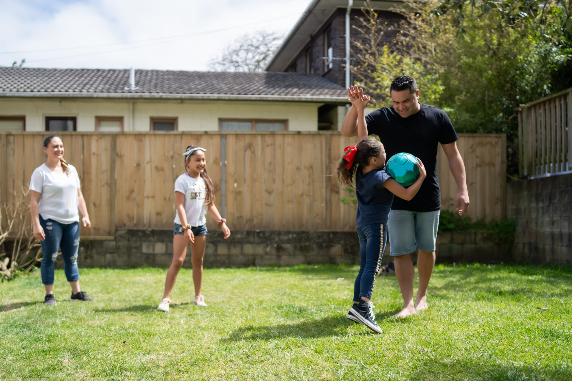 Two adults and several children play in a backyard