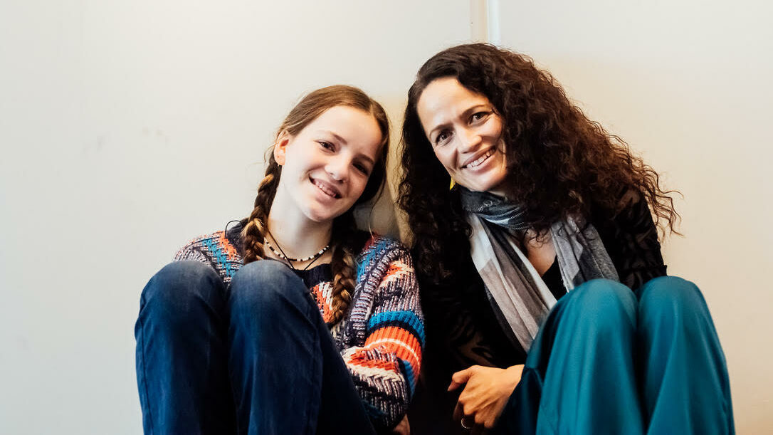 A mother and daughter sit and smile