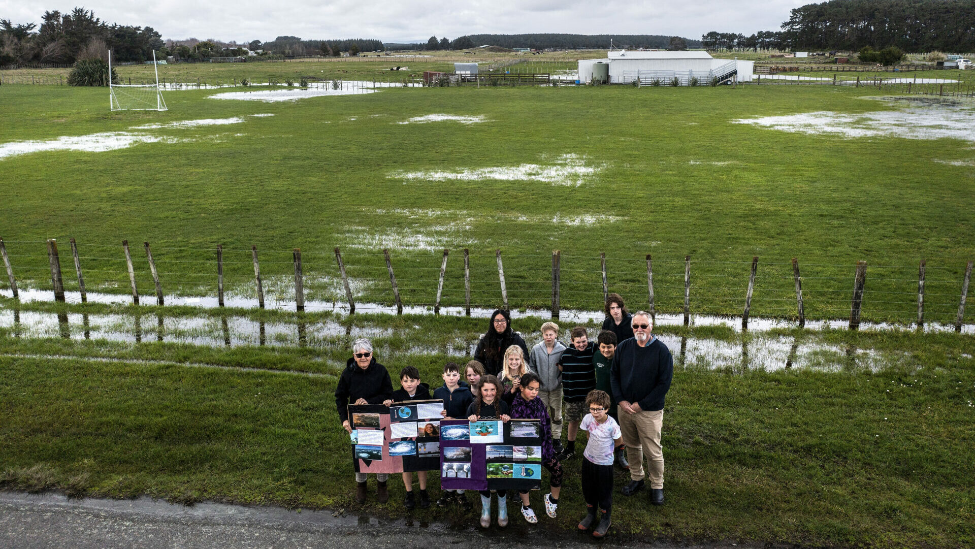 Image credit: Stuff Limited (David Unwin). Children in front of flooding on paddock