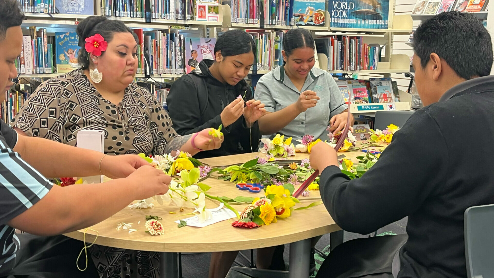 A group of people creating lei in a library
